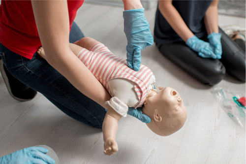 Personne en train d'apprendre les gestes de premiers secours pédiatriques sur un mannequin nourrisson